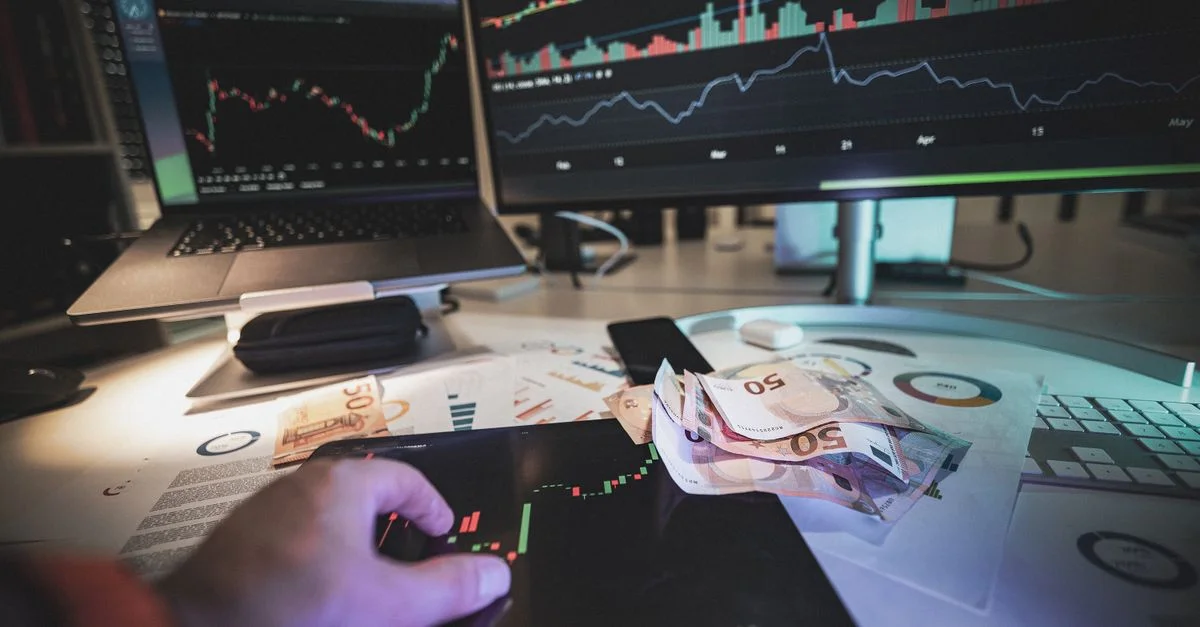 Un bureau de trading moderne avec des écrans montrant des graphiques de marché et des billets en euros, capturant une atmosphère de trading.