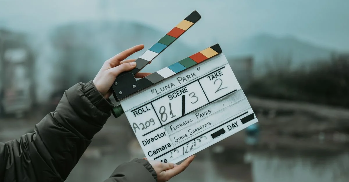 Gros plan sur un clap de film sur un plateau extérieur, signalant le début de la scène.