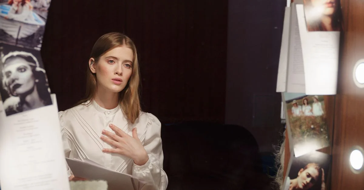 Une actrice contemplative dans une loge, lisant un scénario devant un miroir illuminé.