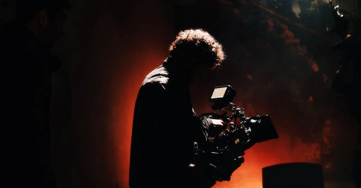 Un cameraman professionnel capture des images dans un cadre créatif et lumineux, éclairé par une lumière chaude.