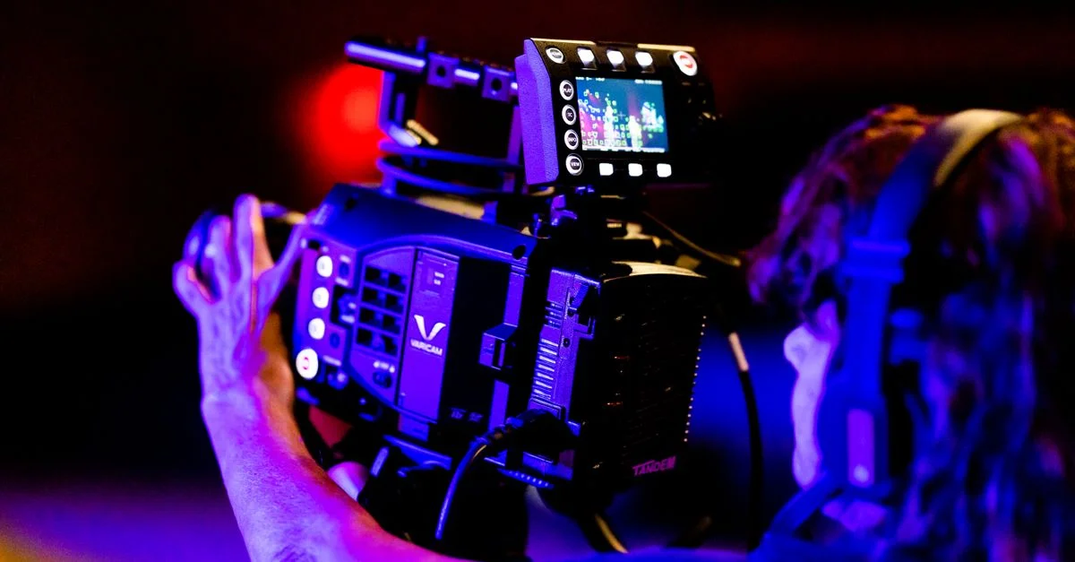 Opérateur de caméra utilisant un équipement professionnel dans un studio TV faiblement éclairé.