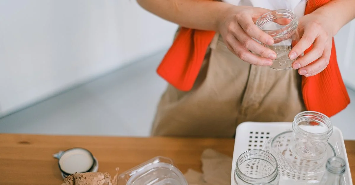 Une femme triant des bocaux en verre dans une benne de recyclage à la maison. Vie éco-responsable.